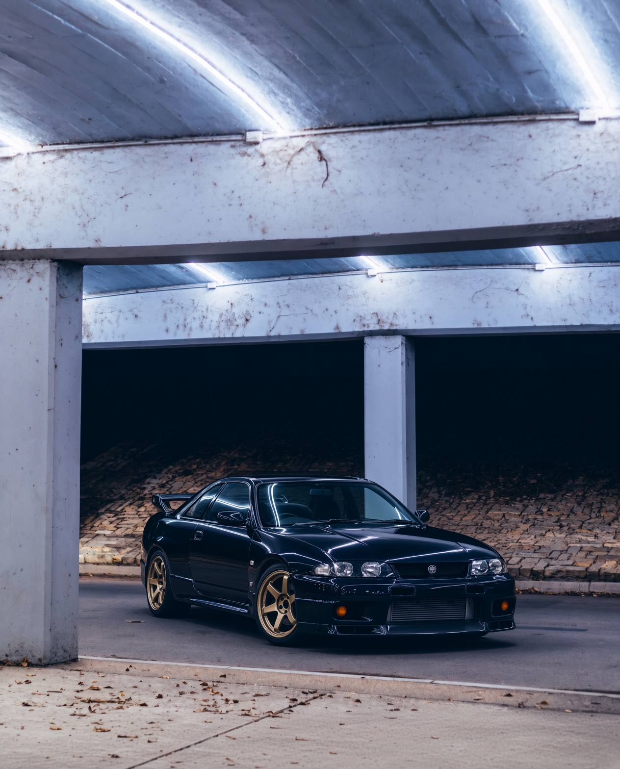 Midnight purple Nissan Skyline GT-R R33 under an overpass